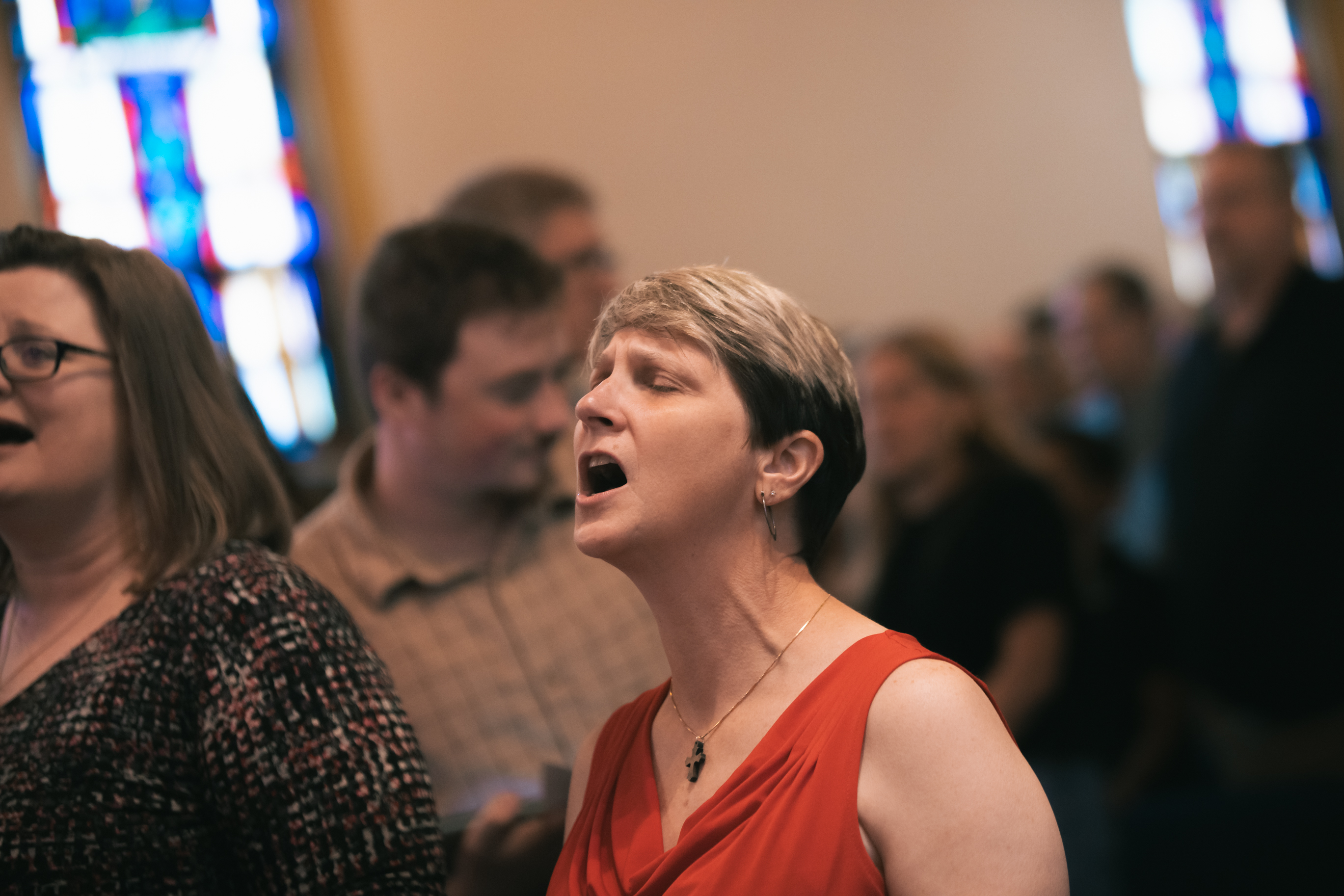 Woman singing worship with stained glass behind her